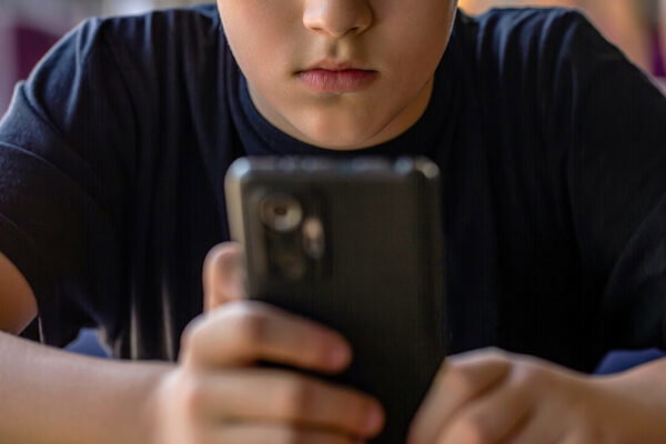 Boy with a serious face communicates on Internet. Child gadget addiction. Child, teenager or preteen mobile phone. Mobile addiction, digital dependence concept